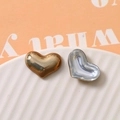 Macro shot of heart-shaped polished metal charms in gold and silver for jewelry making - Brown