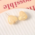 Dettaglio di ciondoli a cuore in resina glitterata con scaglie dorate e ganci in metallo - Beige