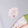 Detail of pink crystal chips ring with white floral bead on a reflective mirror surface - White Flower