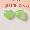 Close-up of green marble pattern heart-shaped resin charms on a white ceramic plate - Green