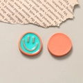 Detail of two-tone enamel smiley face resin charms showing front and back texture - Green Orange
