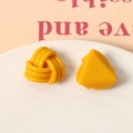 Détail de boucles d'oreilles en résine jaune avec formes de spirale et triangle - Jaune
