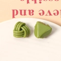 Détail macro de boucles d'oreilles en résine vert olive avec nœud tressé et triangle - Vert fruit