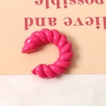 Dettaglio di un accessorio in resina rosa acceso a forma di C intrecciata per gioielli - Rosso rosa