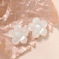 Detailed close-up of white translucent resin flower studs with glitter finish on pink paper - Flower