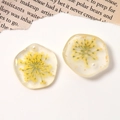 Macro detail of handmade resin charms with yellow dried flowers, gold foil and pearls - Yellow