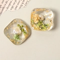 Macro shot of geometric resin patches with gold foil and green dried flowers for DIY crafts - White