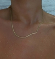 Détail du collier chaîne serpent dorée avec étiquette NECK LINE sur peau mouillée, étanche - 40+5cm / Or