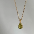 Detailed view of teardrop yellow-green gemstone pendant on gold link chain necklace - August