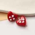 Macro shot of red heart-shaped glass beads with white flower patterns and gold hooks - Red Heart