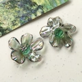 Detail of translucent iridescent resin daisy charms with green centers for DIY jewelry making - Smoke