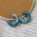 Dettaglio di orecchini a C in resina marmorizzata con perni in argento S925 su sfondo vintage - Blu Nebbia
