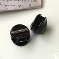 Dettaglio di due piccole mollette per capelli in resina nera lucida con denti a pettine - Nero