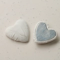Detail of white heart-shaped fabric buttons showing pleated texture and magnetic metal back - White