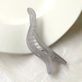 Macro detail of a light grey translucent matte banana hair clip with a minimalist twist design - Smoke