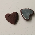 Macro view of heart-shaped fabric buttons with dark brown texture and silver metal base - Coffee