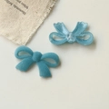 Detail of DIY jewelry findings featuring blue glitter resin and teal flocked bow designs - Blue
