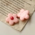 Close-up of pink resin five-petal flower charms on rustic fabric for DIY crafts - Pink