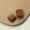 Detail of square resin charms in brown with matte and glossy finishes on felt - Dark Brown