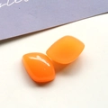 Vista macro de dos dijes de resina naranja translúcida para accesorios de joyería artesanal - Naranja