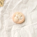 Détail macro d'une breloque ronde en résine avec feuille d'or et nacre pour bijoux DIY - Style Particules Roses