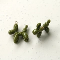 Macro view of olive green balloon dog charms with glossy enamel finish and gold rings - Matcha Green