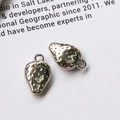 Macro view of two strawberry shaped silver metal charms for DIY jewelry making - Strawberry