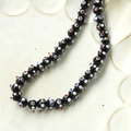 Macro view of colorful handmade glass lampwork eye beads on a white ceramic tray - 1 Piece / Black