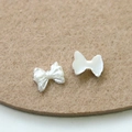 Detalle macro de lazos de perlas blancas para uñas mostrando el frente y la base plana - Estilo con Textura 3D (1)