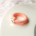 Bague en acrylique orange rose avec un strass rond sur une assiette en céramique - Rose