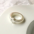 Dettaglio macro di un anello d'argento spesso minimalista con diamante circolare - Argento