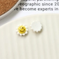 Close-up of DIY acrylic daisy flower charms with smiley face for jewelry making - White