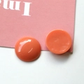 Close-up of glossy coral orange resin half-sphere beads for DIY jewelry making and crafts - Orange