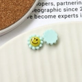 Detailed macro view of pastel blue resin flower charms with smiley face for DIY jewelry - Light Green