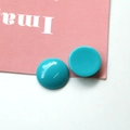 Macro shot of round turquoise resin charm showing smooth polished surface and flat base - Blue