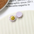 Detailed macro of a purple acrylic flower charm with a yellow smiley face pattern - Purple