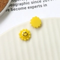 Macro detail of yellow resin sun charm with a minimalist smiley face for DIY jewelry - Yellow