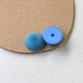Detail eines himmelblauen beflockten Knopfes mit Vorder- und Rückseite für DIY-Handwerk - Blau