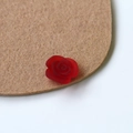 Macro view of a single red frosted resin rose petal charm for DIY crafts and jewelry - Burgundy