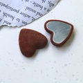Detalle de dijes de corazón flocados en marrón oscuro con reverso de metal plateado - café