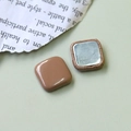 Dettaglio macro di bottoni geometrici quadrati con superficie marrone e base in metallo - Quadrato Marrone Caffè