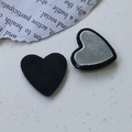 Vue macro d'un bouton cœur en fausse laine avec base en métal argenté pour le DIY - Noir