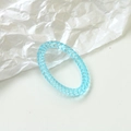 Macro shot of sky blue translucent acrylic spiral ring with woven texture on white paper - Sky Blue