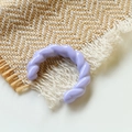 Primo piano di un anello intrecciato in acrilico lavanda su sfondo di tessuto per accessori - Viola Taro