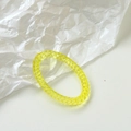Macro shot of yellow candy-colored acrylic spiral ring with textured finish detail - Yellow