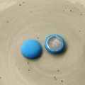 Dettaglio di bottoni rotondi in tessuto azzurro con retro in metallo argento - Blu