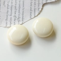 Dettaglio di bottoni tondi in resina crema lucida su uno sfondo di giornale vintage curato - Bianco