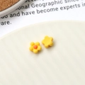 Macro detail of yellow acrylic flower charms for DIY jewelry making on white ceramic - Yellow