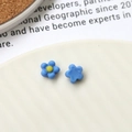 Macro shot of two small blue resin sunflower charms for DIY jewelry and nail art - Blue