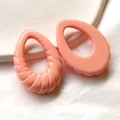 Dettaglio macro di ciondoli in acrilico rosa corallo a forma di goccia con texture a spirale - Rosa